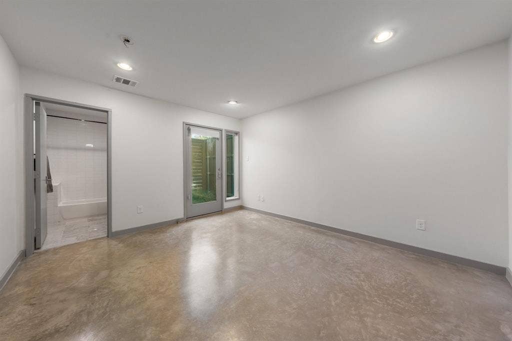 Polished concrete flooring, recessed lighting, neutral wall palette, glass-panel entry door, and matching interior trim
