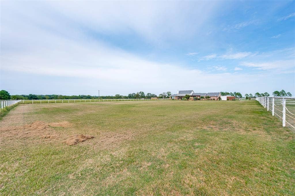 Expansive pasture land featuring perimeter post-and-rail fencing and open terrain