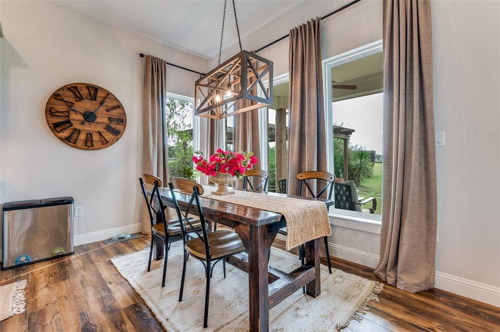 Dining area featuring wood-finish flooring, floor-to-ceiling windows, and a structured metal-frame pendant light fixture