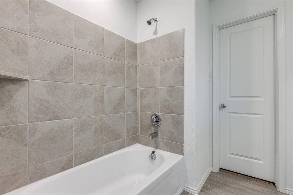 9216 Grackle Place, McKinney, TX 75071 Bathroom with hardwood / wood-style flooring and tiled shower / bath combo
