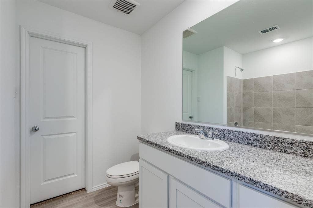 9216 Grackle Place, McKinney, TX 75071 Bathroom featuring a shower, hardwood / wood-style floors, vanity, and toilet