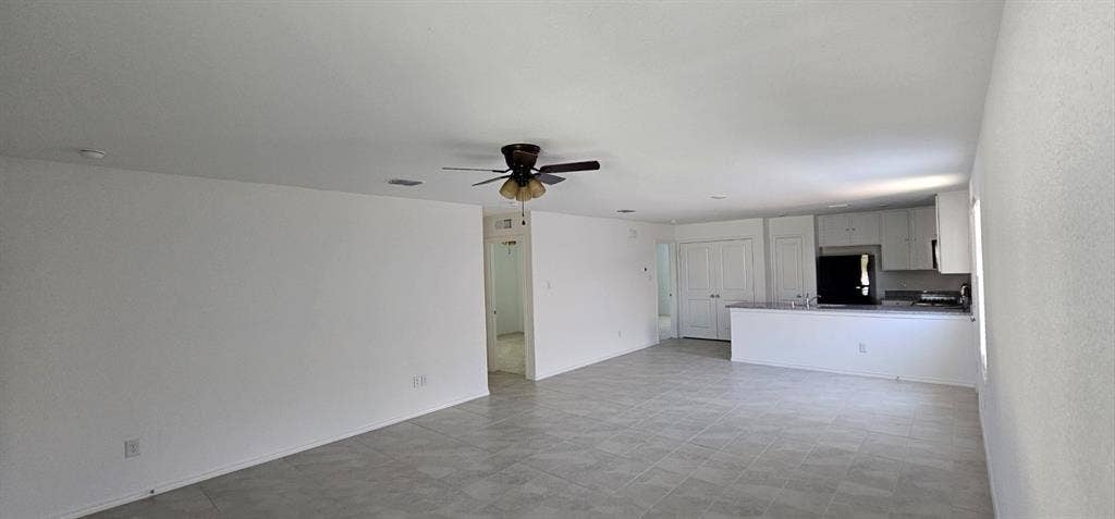 9216 Grackle Place, McKinney, TX 75071 Unfurnished living room with a ceiling fan and baseboards
