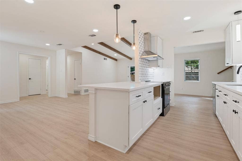 417 Keats Circle, Irving, TX 75061 Kitchen featuring a central island with a solid-surface countertop, white shaker-style cabinetry, stainless steel range hood, patterned tile backsplash, and wood-finish flooring