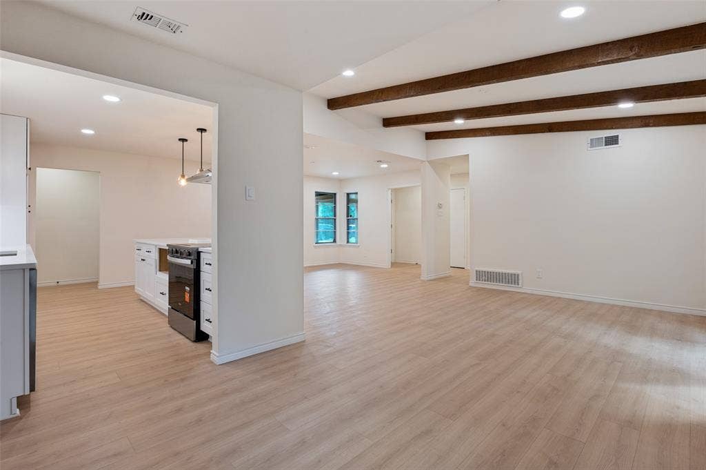 417 Keats Circle, Irving, TX 75061 Open interior space featuring wood-finish flooring, exposed ceiling beams, recessed lighting, and kitchen cabinetry with a stainless steel range