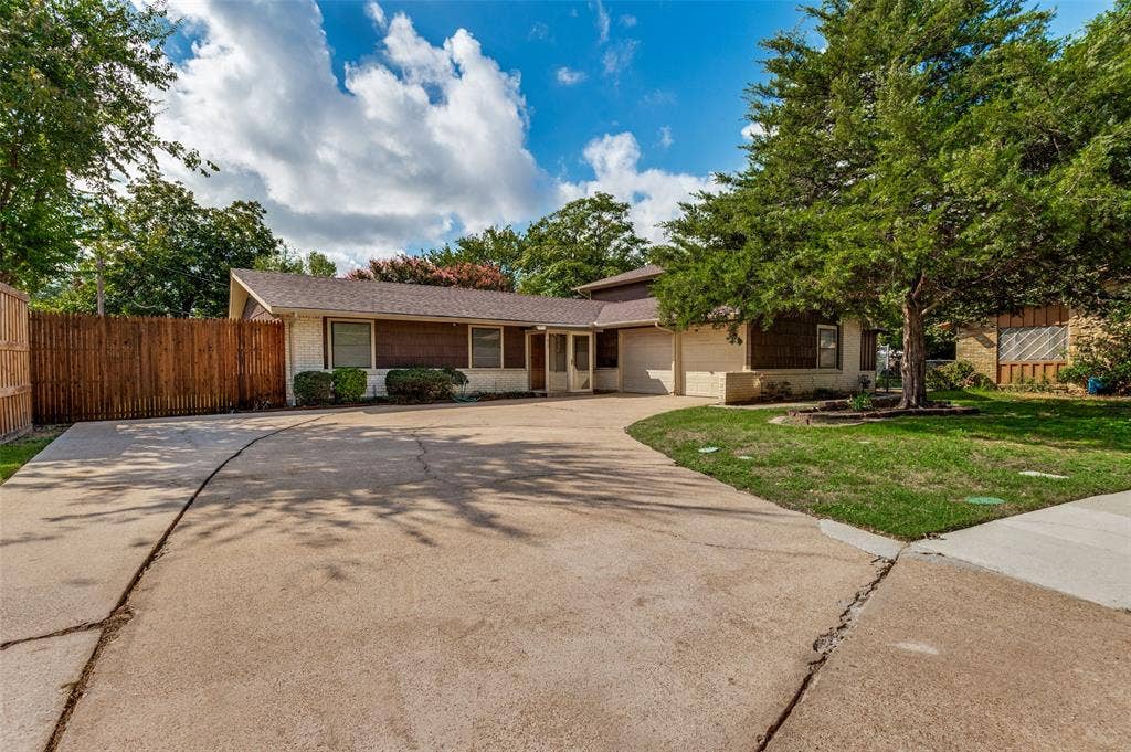 417 Keats Circle, Irving, TX 75061 Single-story exterior featuring light-toned brick masonry, horizontal wood-toned siding, a concrete driveway, and an attached garage