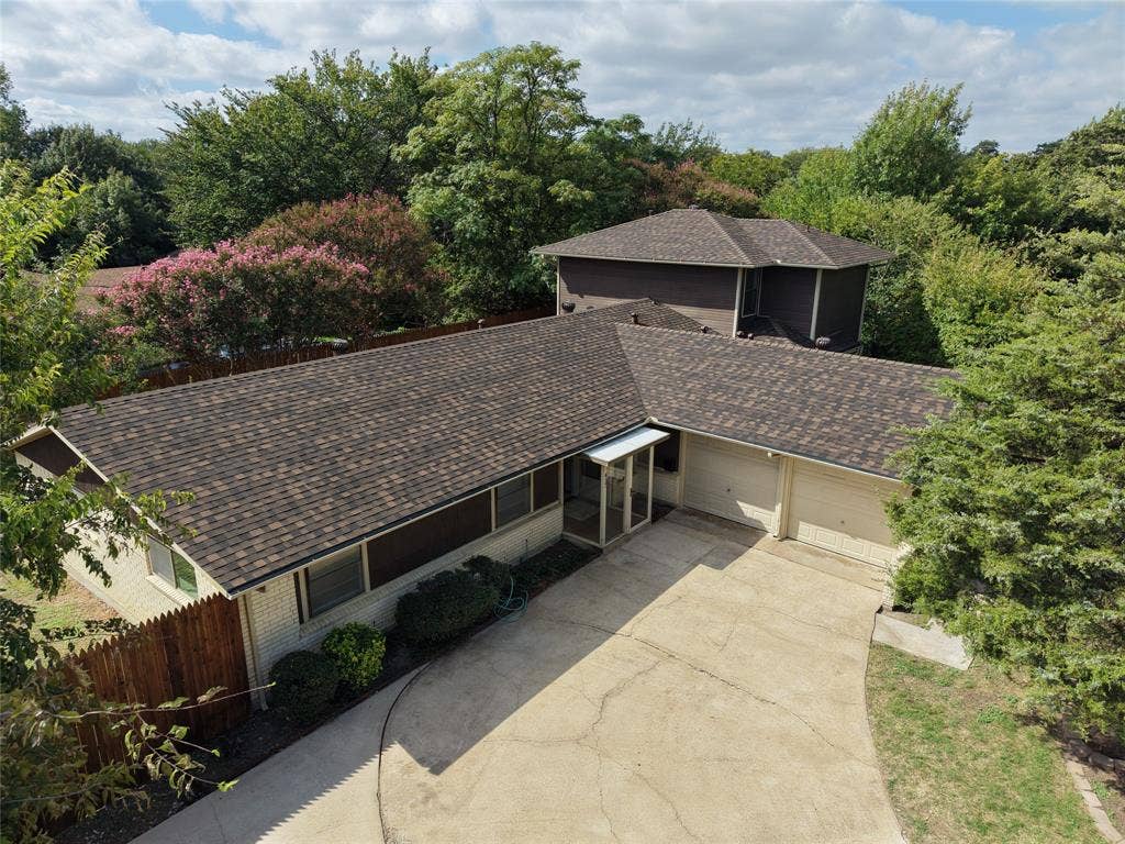 417 Keats Circle, Irving, TX 75061 Multi-level exterior featuring a brick and horizontal siding facade, composite shingle roof, two-car garage, and mature tree landscaping