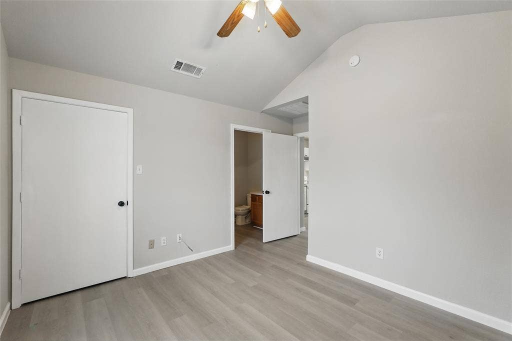 Vaulted ceilings, wood-finish flooring, and a ceiling-mounted light fixture with a fan