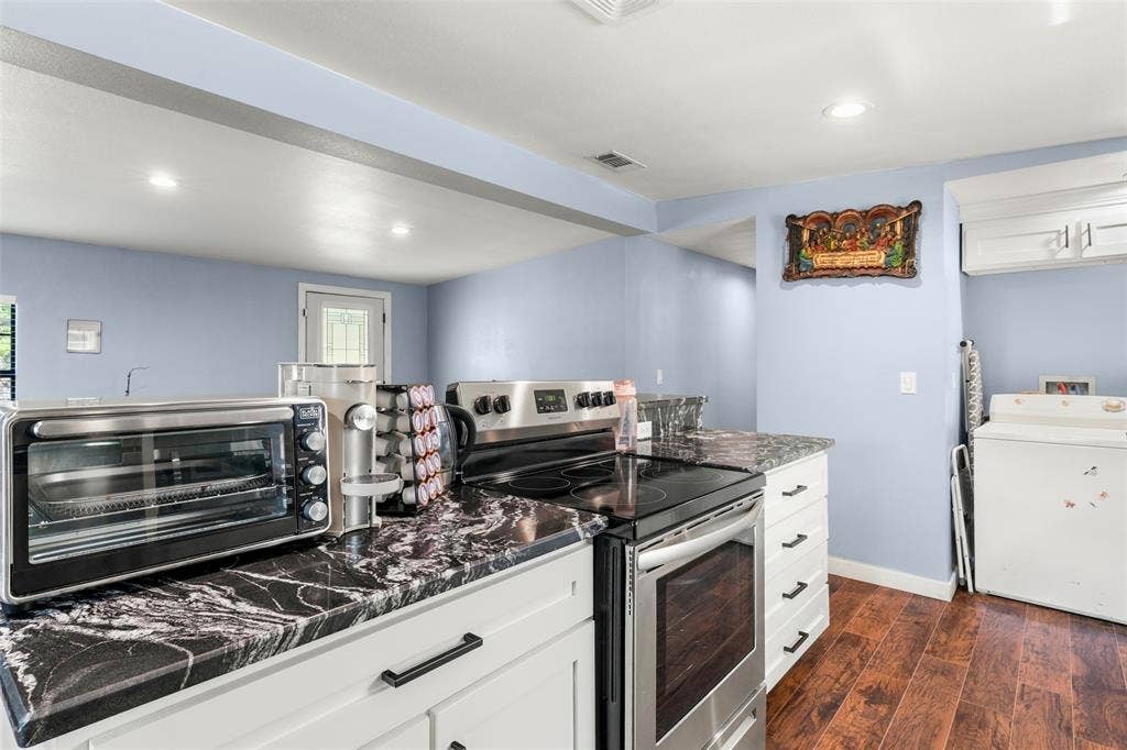 1219 Green Tree Acres Road, Kemp, TX 75143 Kitchen featuring dark stone-patterned countertops, white shaker-style cabinetry with matte black hardware, stainless steel electric range, and wood-finish flooring