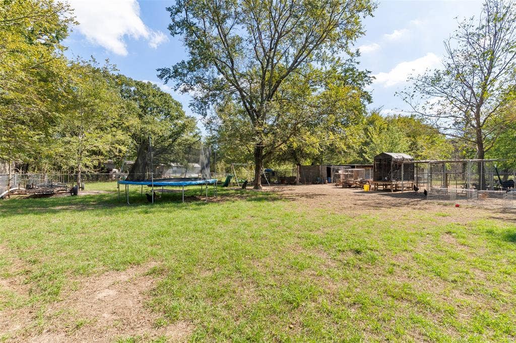 1219 Green Tree Acres Road, Kemp, TX 75143 Expansive lot featuring mature trees, perimeter wire fencing, and multiple external structures