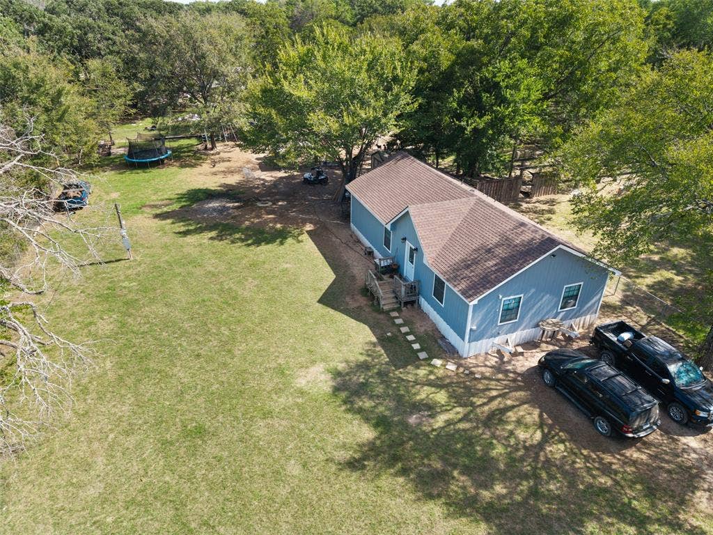 1219 Green Tree Acres Road, Kemp, TX 75143 Single-story residence featuring blue siding, a composite shingle roof, wood-frame deck, and expansive grounds with mature trees