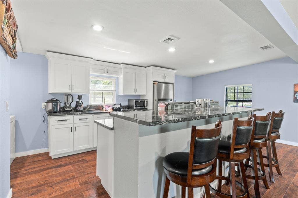 1219 Green Tree Acres Road, Kemp, TX 75143 Kitchen featuring white cabinetry, stone-finish countertops, an expansive breakfast bar, recessed lighting, and wood-finish flooring