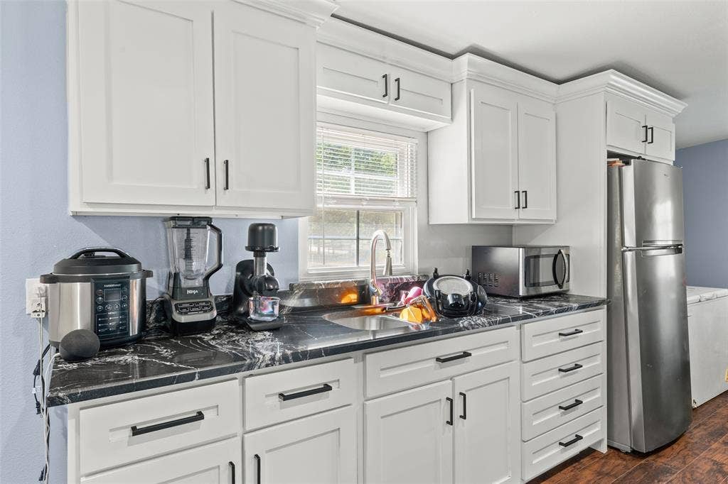 1219 Green Tree Acres Road, Kemp, TX 75143 Kitchen featuring shaker-style white cabinetry, dark stone-finish countertops, stainless steel undermount sink with arched faucet, and recessed hardware