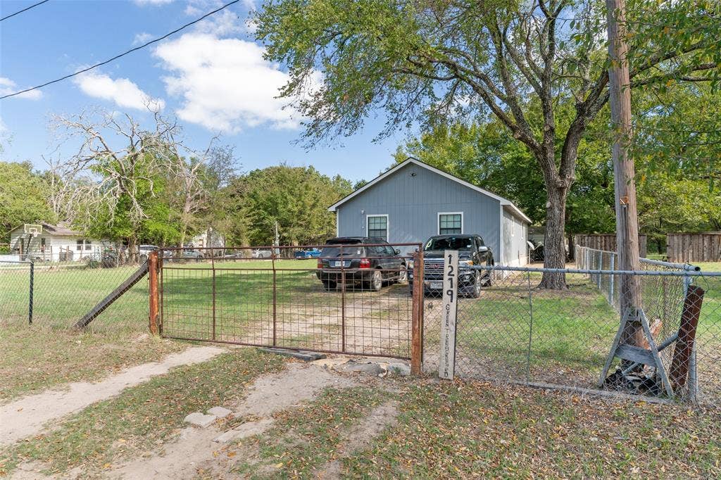 1219 Green Tree Acres Road, Kemp, TX 75143 Single-story residence with vertical siding, gable roof, metal perimeter fencing, and dual-panel metal gate
