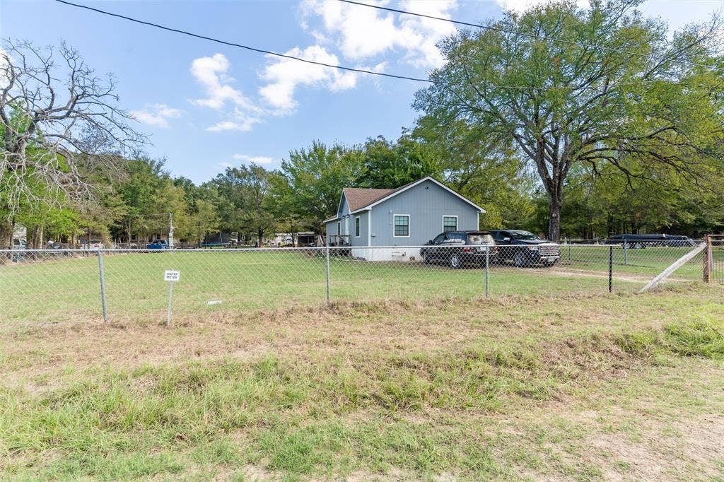 1219 Green Tree Acres Road, Kemp, TX 75143 Gabled-roof residence featuring lap siding, an expansive fenced lot, mature trees, and a gravel driveway