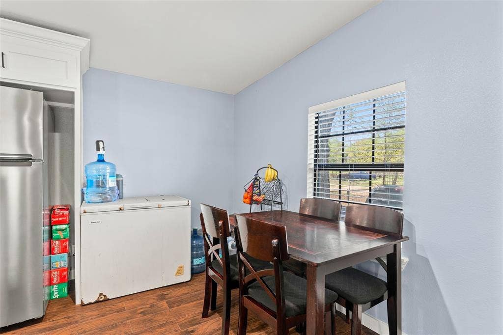1219 Green Tree Acres Road, Kemp, TX 75143 Kitchen area featuring wood-finish flooring, white cabinetry, stainless steel refrigerator, and a window with horizontal blinds