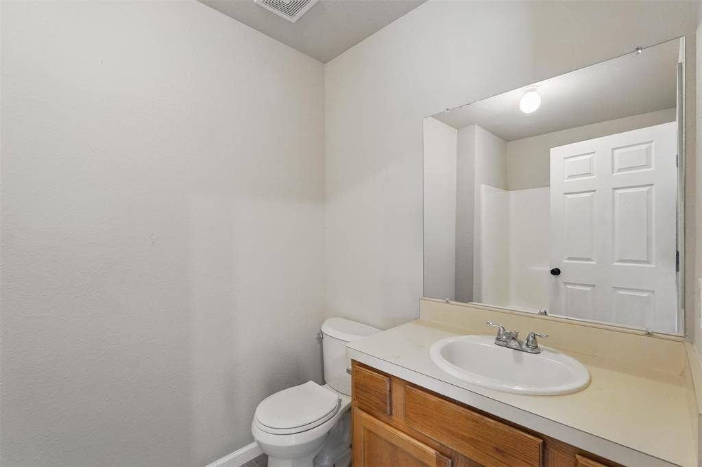 Full-width vanity with a wood-finish cabinet, integrated basin, dual-handle faucet, and large wall-mounted mirror