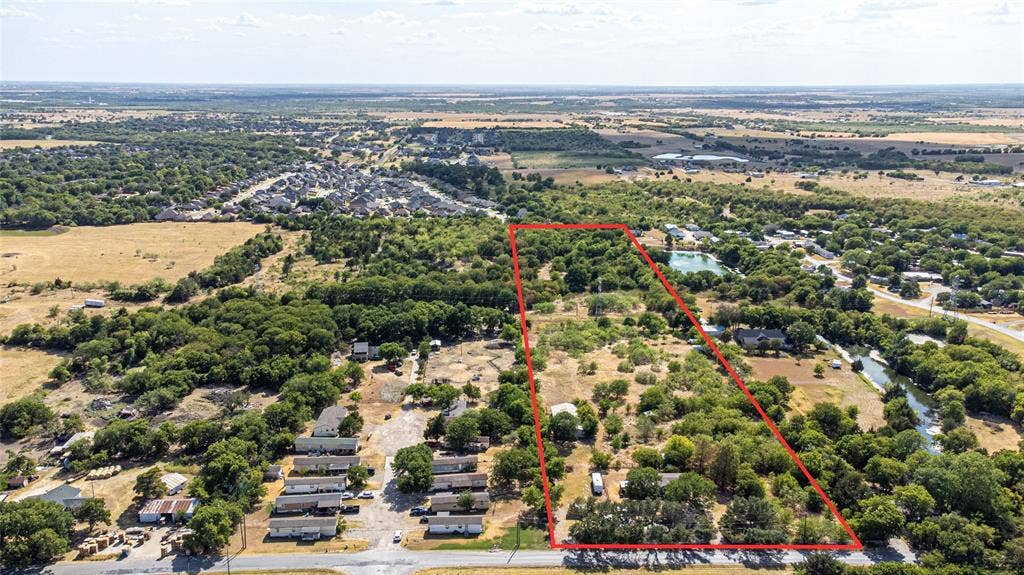 Expansive rectangular parcel featuring mature trees, diverse natural vegetation, and direct road frontage