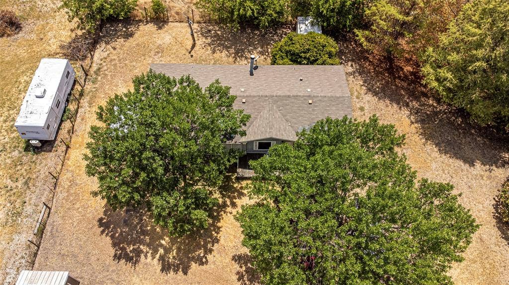 Expansive lot featuring mature trees, partial perimeter fencing, and an asphalt shingle roof