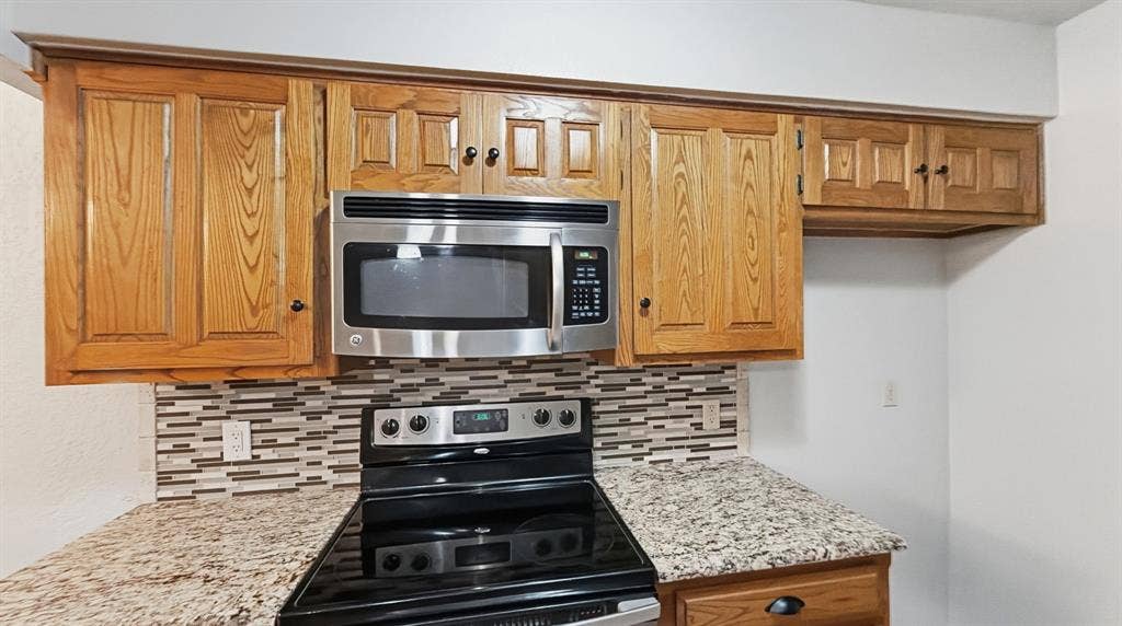 1903 W Spanish Oak Drive, Granbury, TX 76048 Stove and microwave view with granite
