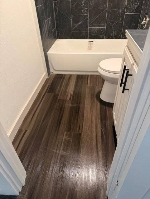 1613 Campbell Street, #A, Commerce, TX 75428 Bathroom featuring wood-finish flooring, dark stone-patterned tile shower surround, and vanity with dark hardware