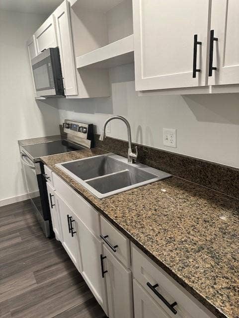 1613 Campbell Street, #A, Commerce, TX 75428 Kitchen featuring white shaker-style cabinetry with matte black hardware, stone-patterned countertops, stainless steel dual-basin sink with gooseneck faucet, integrated stainless steel microwave, and wood-finish flooring