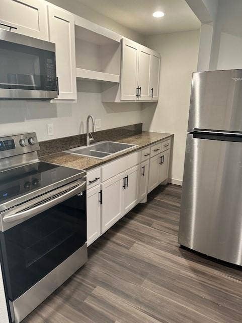 1613 Campbell Street, #A, Commerce, TX 75428 Kitchen featuring white cabinetry with matte black hardware, stainless steel appliances, stone-surface countertops, dual-basin stainless steel sink, and wood-finish flooring