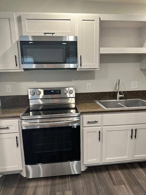 1613 Campbell Street, #A, Commerce, TX 75428 Kitchen featuring white cabinetry with matte black hardware, stainless steel electric range, over-the-range microwave, dark stone-finish countertops, and dual-basin sink with arched faucet