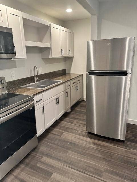 1613 Campbell Street, #A, Commerce, TX 75428 Kitchen featuring white shaker-style cabinetry, stainless steel appliances, dark stone-finish countertops, stainless steel dual-basin sink with arched faucet, and wood-finish flooring