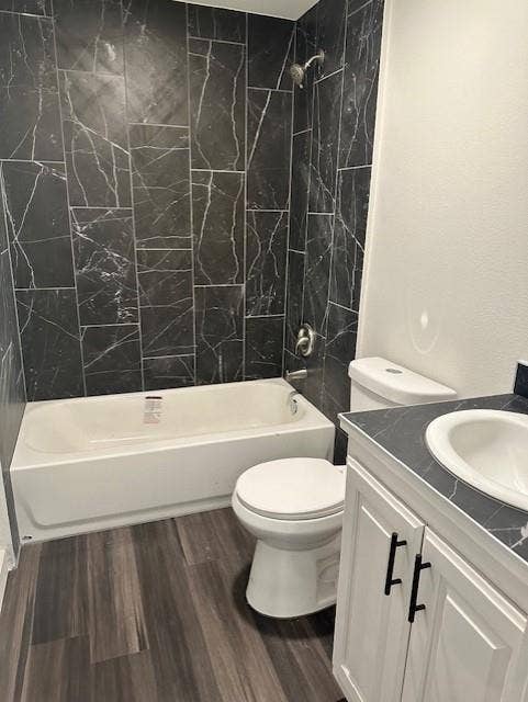 1613 Campbell Street, #A, Commerce, TX 75428 Bathroom featuring floor-to-ceiling dark stone-finish wall tile, white vanity with black hardware, integrated sink with stone-finish countertop, and wood-finish flooring