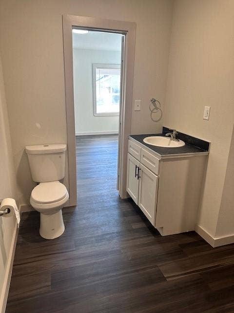 1613 Campbell Street, #A, Commerce, TX 75428 Bathroom featuring wood-finish flooring, a white vanity with dark hardware, a surface-mount sink with a chrome faucet, and a wall-mounted metal towel ring