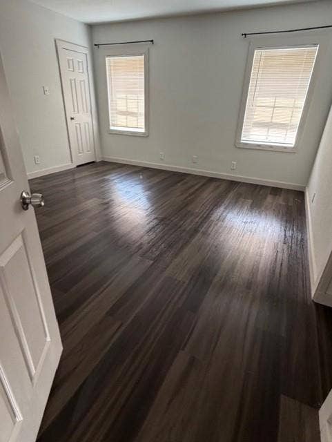 1613 Campbell Street, #A, Commerce, TX 75428 Neutral interior space featuring wood-finish flooring, two windows with horizontal blinds, and a paneled door