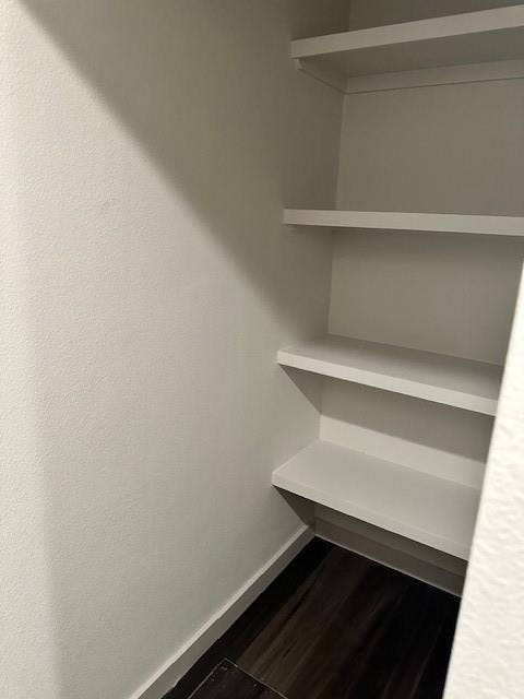 1613 Campbell Street, #A, Commerce, TX 75428 Built-in closet featuring three tiers of fixed white shelving and dark wood-finish flooring