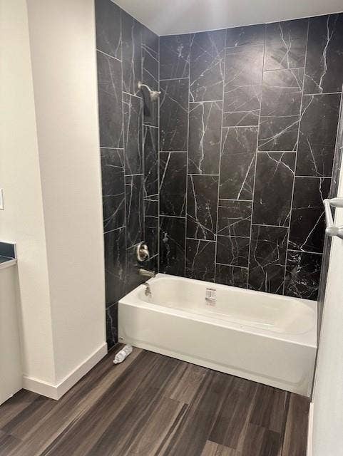 1613 Campbell Street, #A, Commerce, TX 75428 Bathroom featuring a white bathtub, full-height wall surround with large-format dark patterned tile, and wood-finish flooring