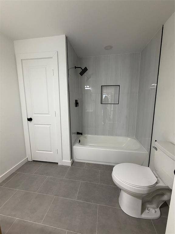 Bathroom featuring oversized grey floor tiling, a tub-shower combination with vertical wall tile, an integrated recessed shower niche, and matte black plumbing fixtures