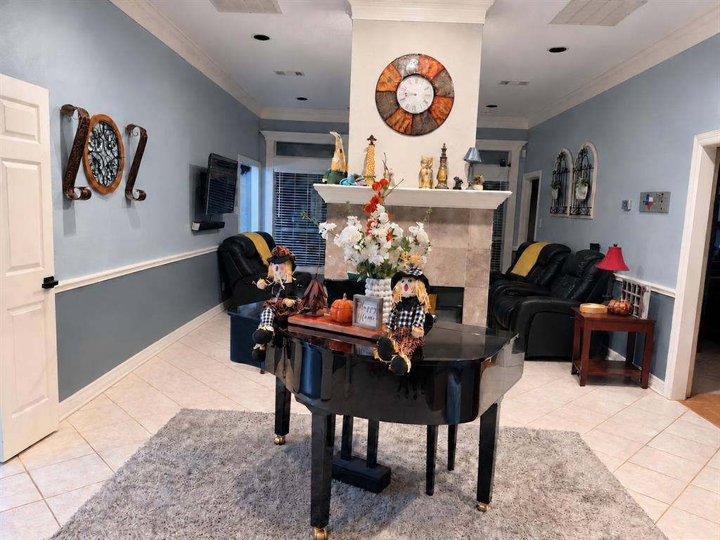 605 Edgewood Lane, Ovilla, TX 75154 Living space featuring a central fireplace with stone-tile surround, tile flooring, recessed lighting, crown molding, and chair rail wainscoting