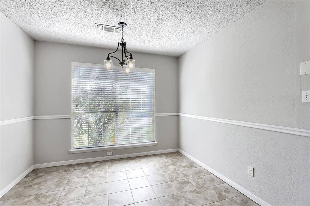 2039 Angelica Way, Dallas, TX 75217 Neutral-toned interior space featuring light-colored tile flooring, chair rail molding, and a metal multi-light chandelier