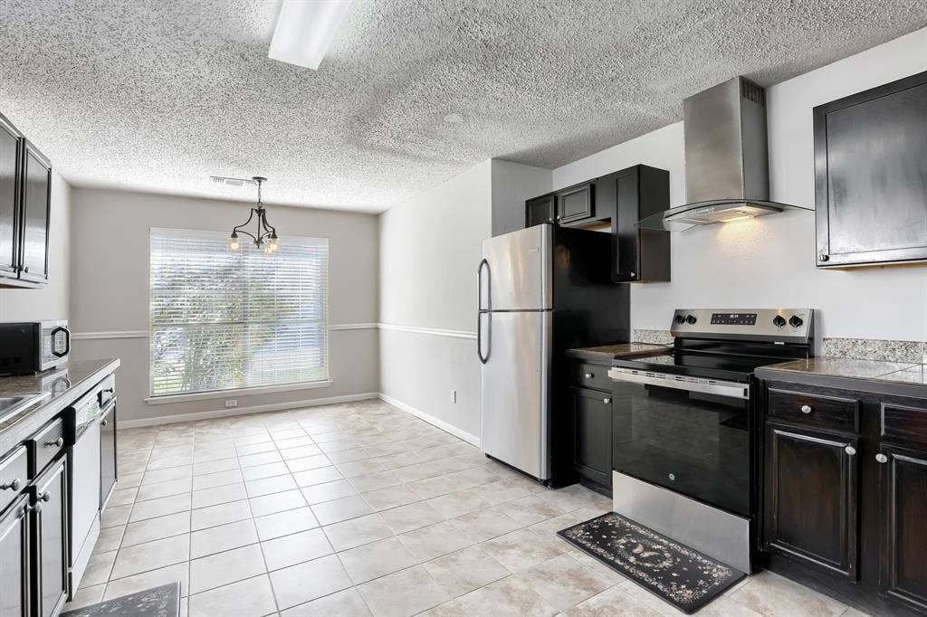 2039 Angelica Way, Dallas, TX 75217 Kitchen featuring dark cabinetry, stone-finish countertops, a stainless steel range with a glass-canopy vent hood, and tile flooring