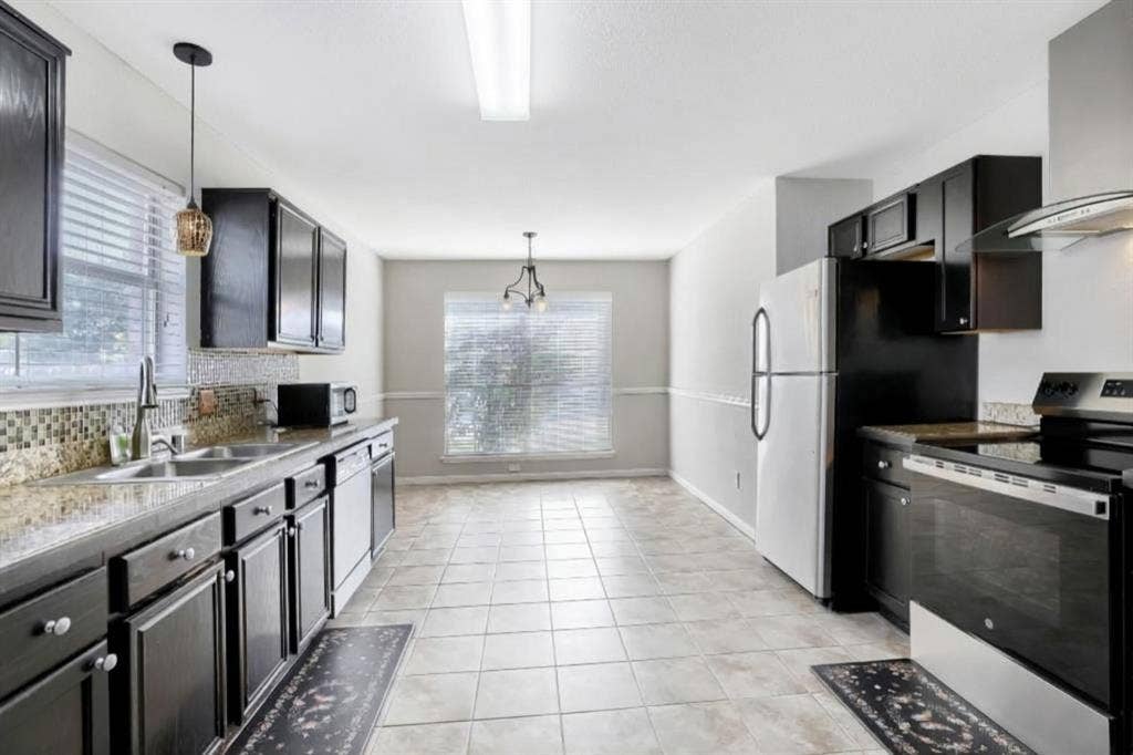 2039 Angelica Way, Dallas, TX 75217 Kitchen featuring dark cabinetry, mosaic tile backsplash, stone-finish countertops, stainless steel appliances, and tile flooring