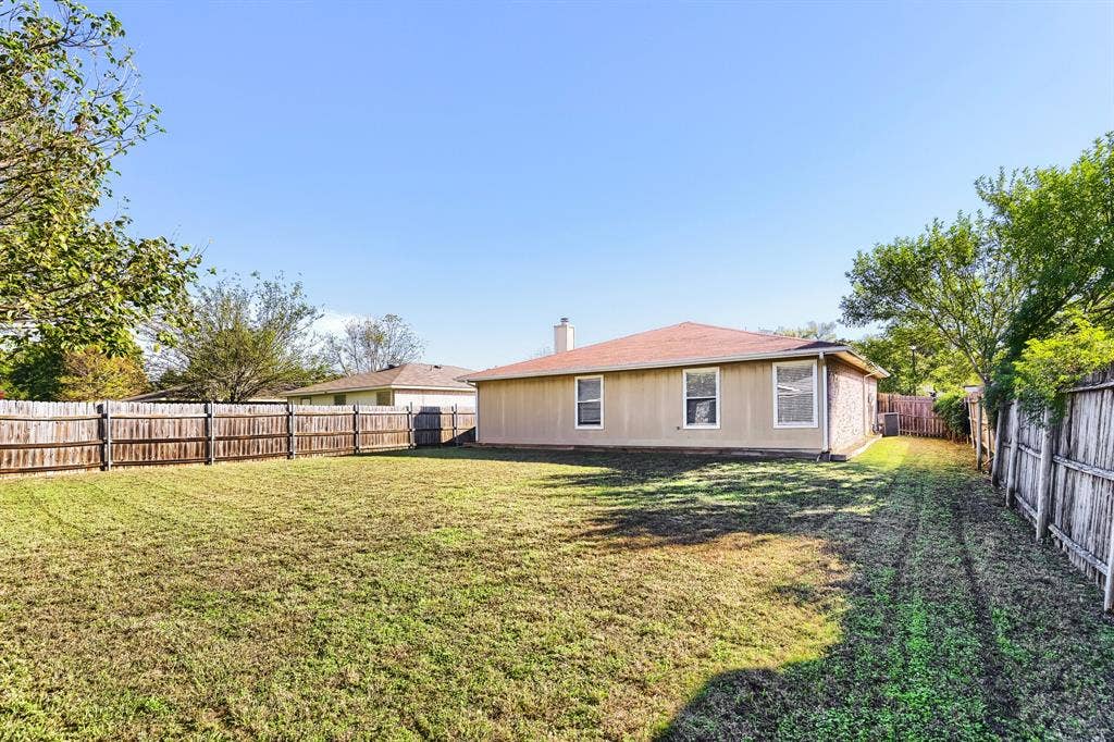 2039 Angelica Way, Dallas, TX 75217 Spacious backyard featuring a grass lawn, perimeter wood fencing, and mature trees