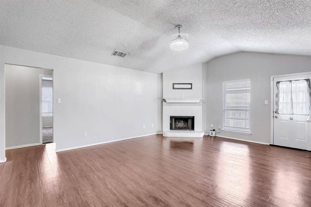 2039 Angelica Way, Dallas, TX 75217 Vaulted ceilings, wood-finish flooring, corner fireplace with white hearth, and integrated globe lighting