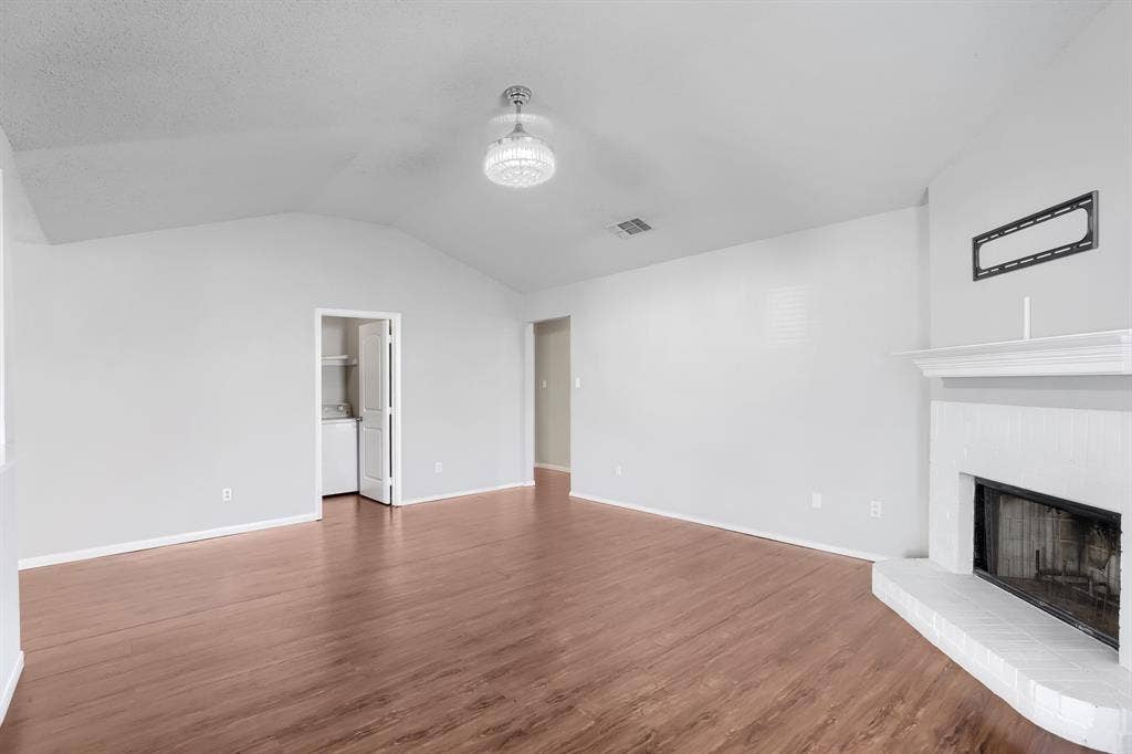 2039 Angelica Way, Dallas, TX 75217 Vaulted ceilings, wood-finish flooring, painted brick fireplace with a mantle, and a modern glass-cased ceiling light fixture