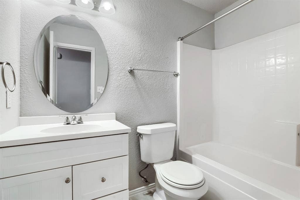 2039 Angelica Way, Dallas, TX 75217 Bathroom featuring a white vanity with an integrated sink, oval wall-mounted mirror, three-light fixture, and a white tiled shower-tub combination