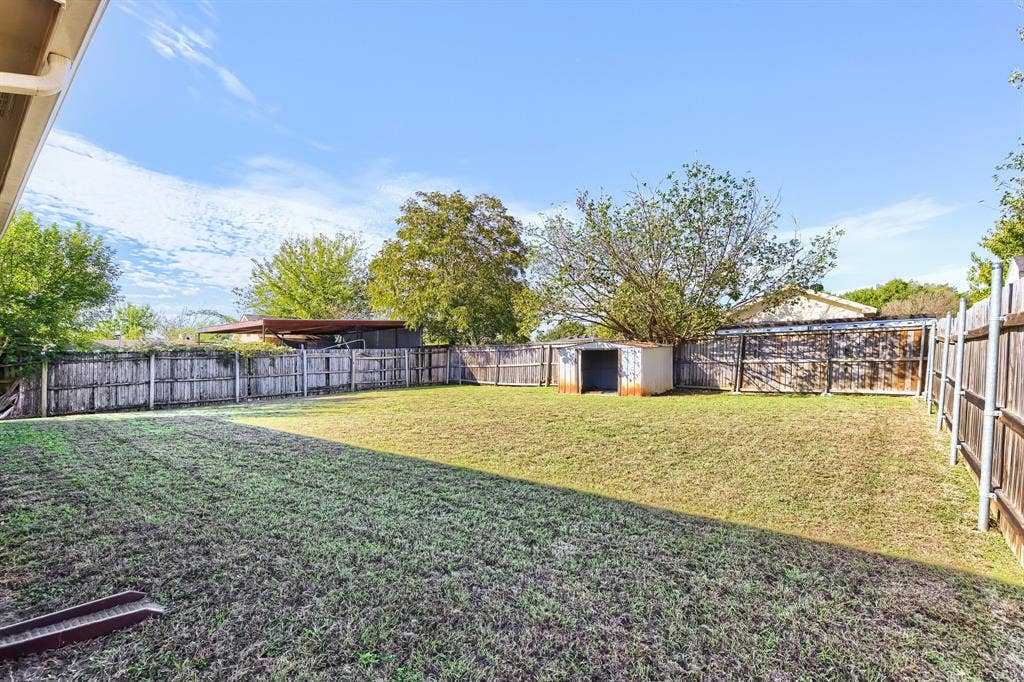 2039 Angelica Way, Dallas, TX 75217 Expansive backyard featuring a lawn, full-perimeter wood fencing, and a detached storage structure