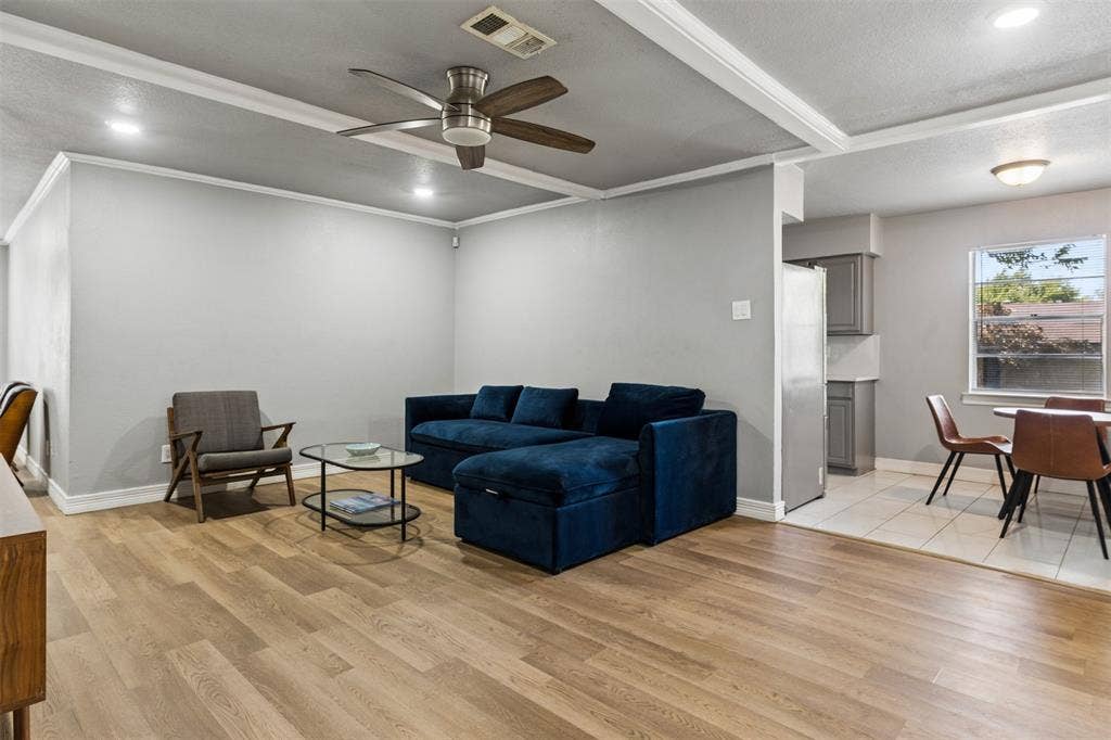 Living area featuring a tray ceiling, recessed lighting, and a multi-blade ceiling fan, complemented by wood-finish flooring throughout