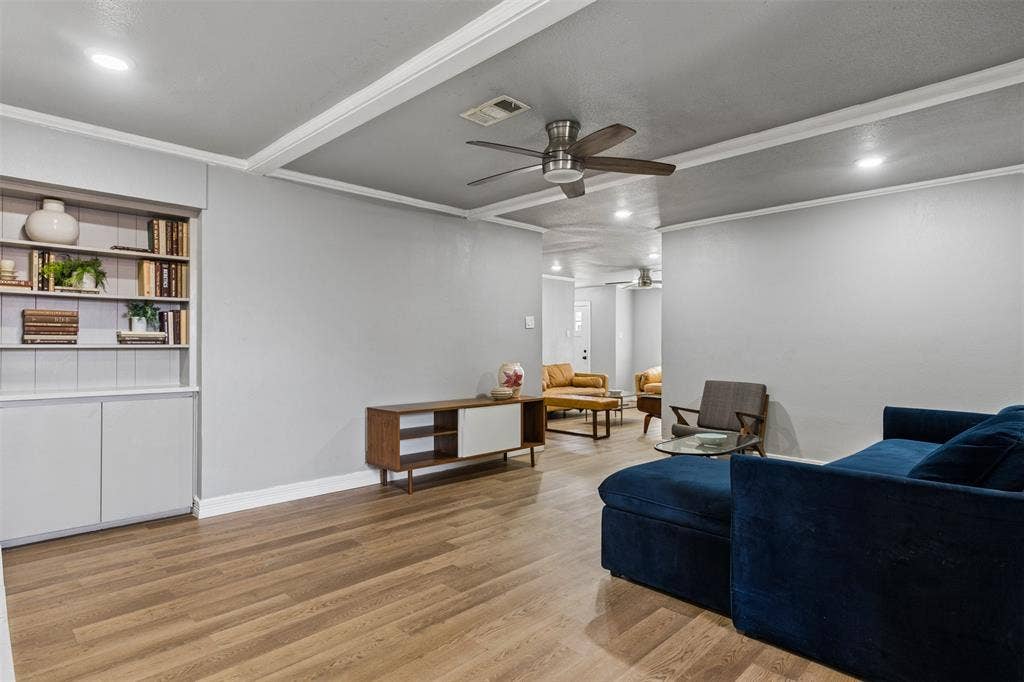 Living area featuring wood-finish flooring, recessed lighting, a ceiling fan, and built-in shelving with lower cabinet storage