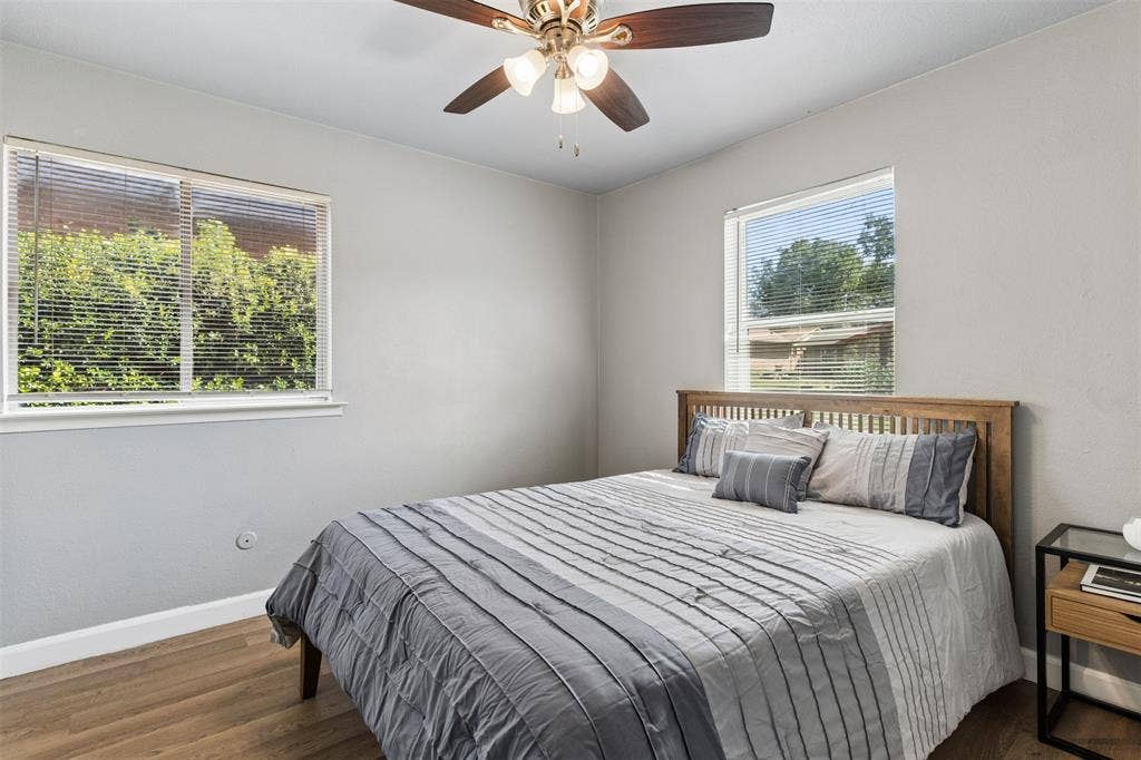 Neutral wall tones featuring wood-finish flooring, dual windows, and a ceiling-mounted fan with integrated light fixtures
