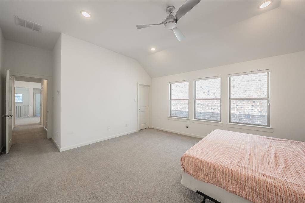 VVaulted ceilings featuring recessed lighting and a brushed-metal ceiling fan, three double-pane windows, and neutral carpeting in the primary bedroom