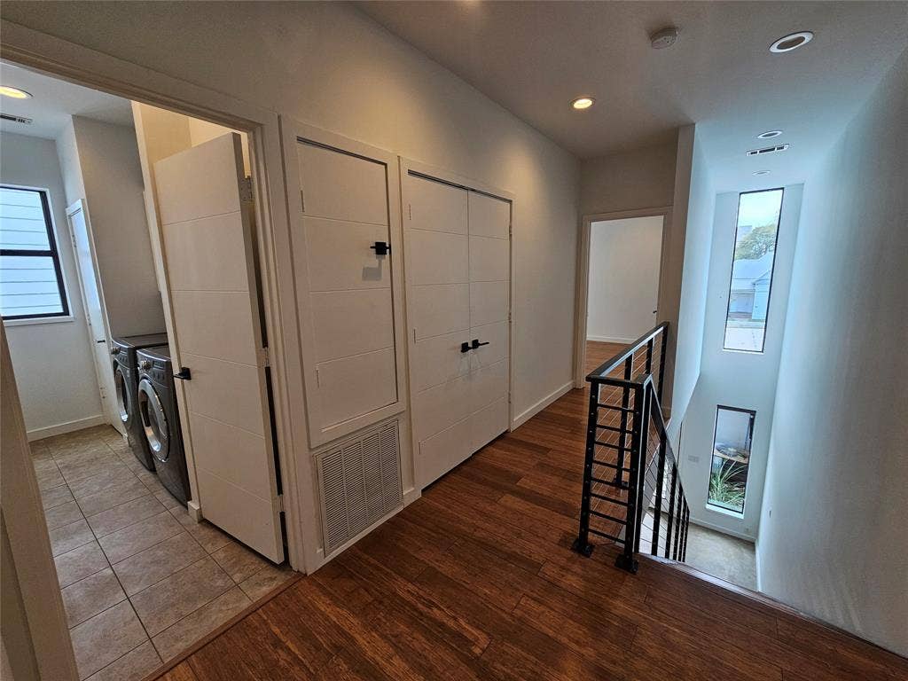4215 Roseland Avenue, Dallas, TX 75204 Hallway featuring wood-finish flooring, matte black hardware, recessed lighting, and a metal stair railing with vertical balusters