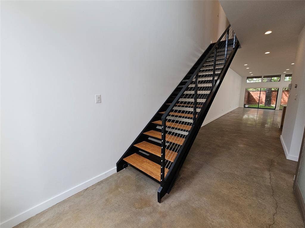 4215 Roseland Avenue, Dallas, TX 75204 Open-tread staircase with wood-finish planks, black metal stringers, and stainless steel cable railing, complemented by polished concrete flooring and recessed ceiling lighting