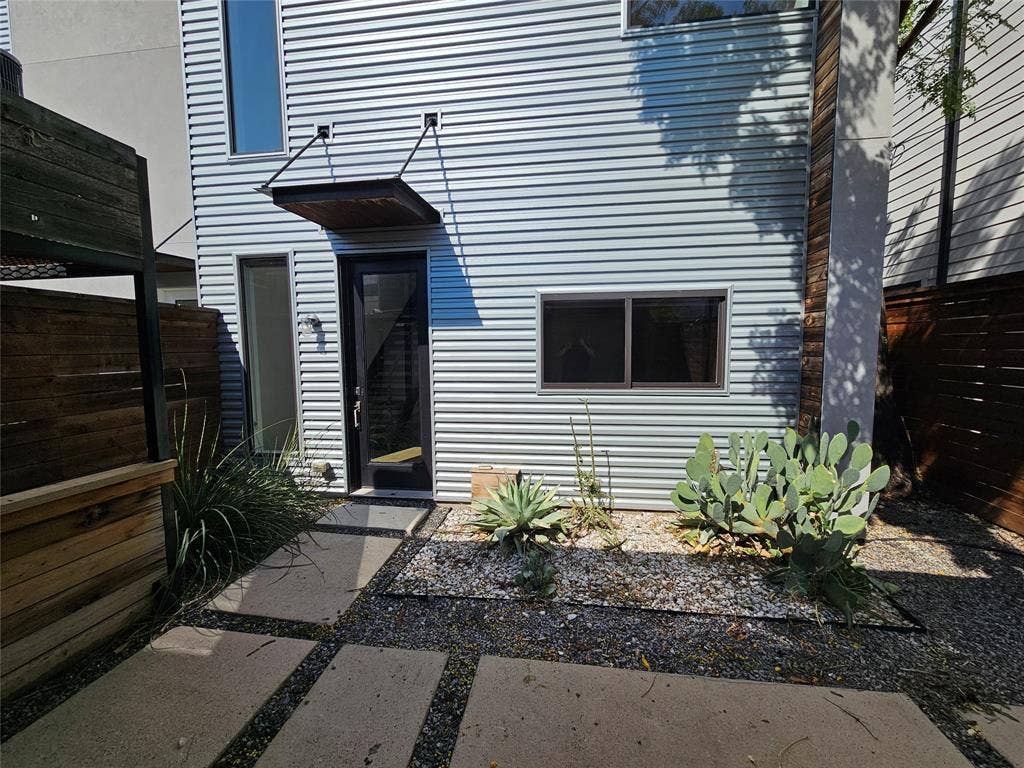 4215 Roseland Avenue, Dallas, TX 75204 Modern exterior featuring horizontal metal siding, cantilevered steel awning, glass-panel door, and custom paver walkway with stone aggregate borders